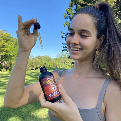 Woman wearing sports wear holding Lifecykel Cordyceps mushroom extract bottle with dropper