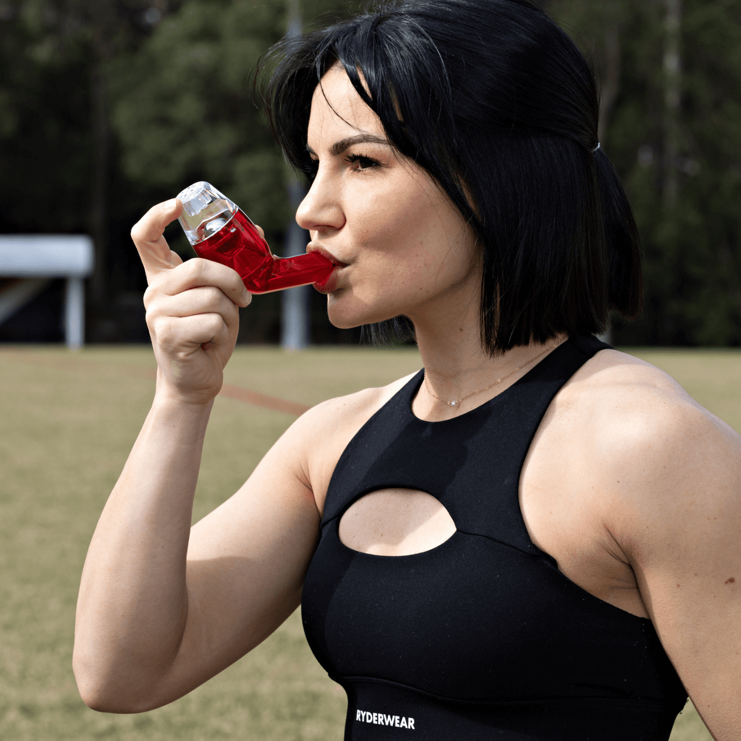 Woman with sports tops using the red breathing device while exercising